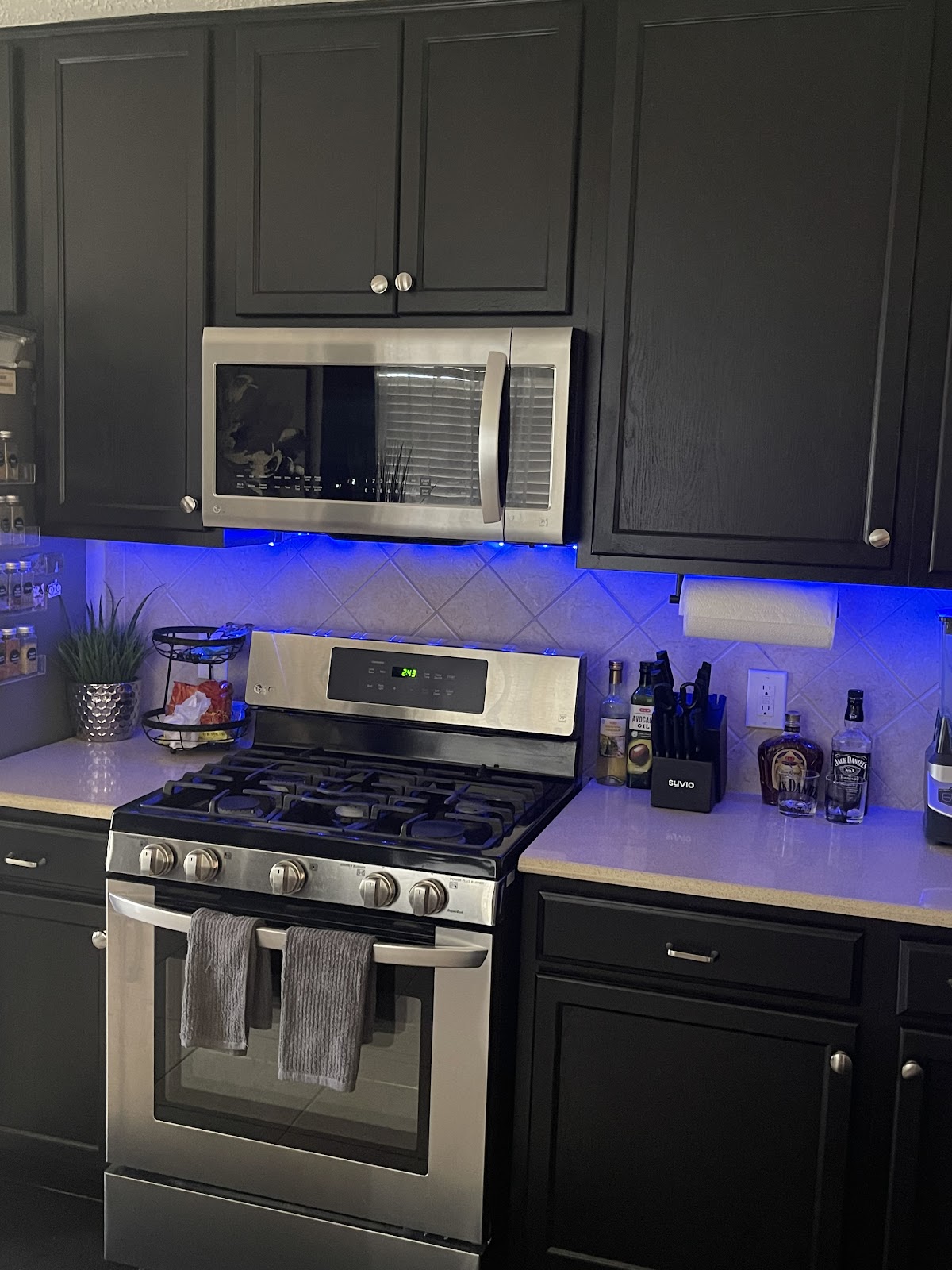 Kitchen cabinets painted dark charcoal with under-cabinet lighting